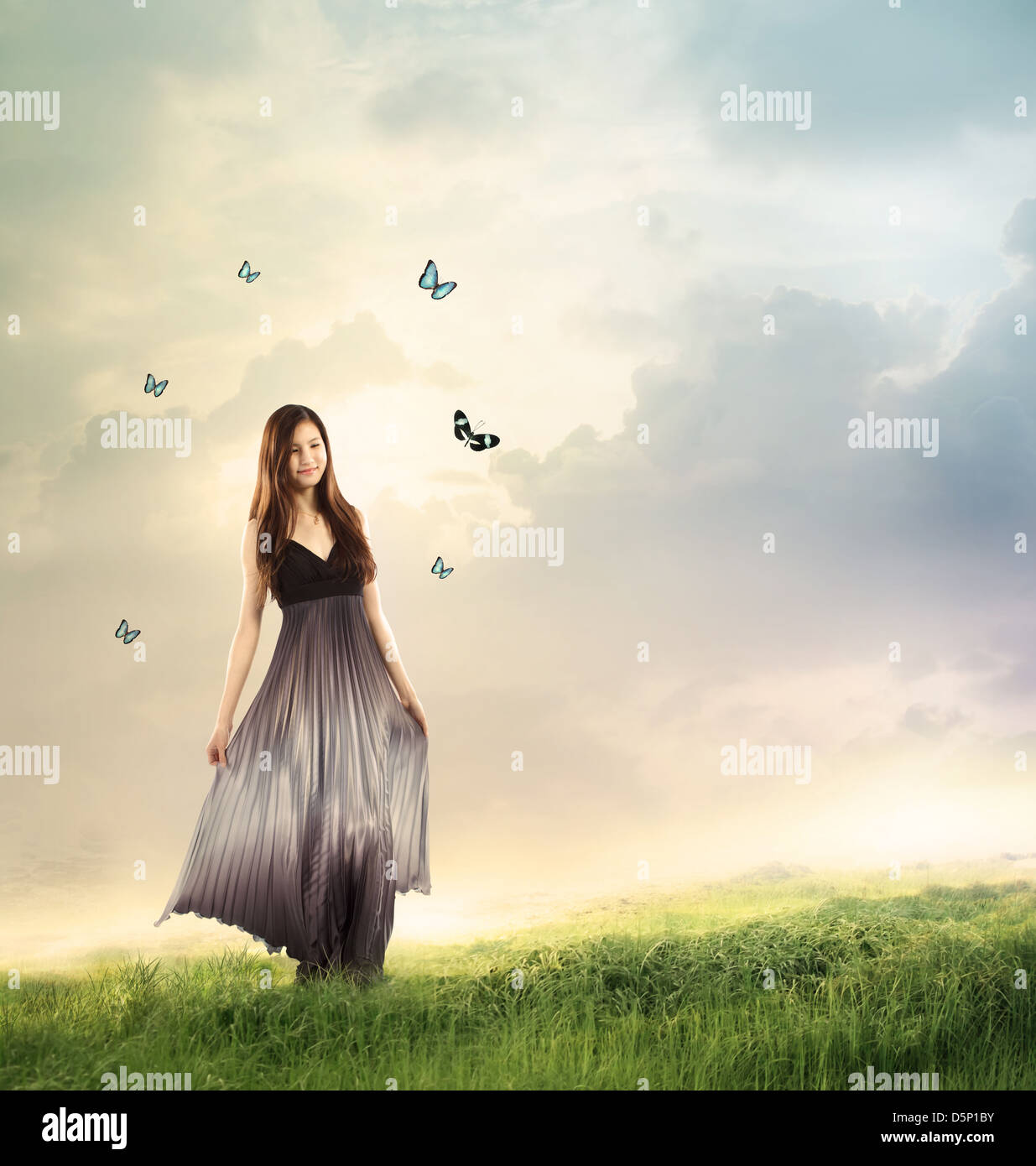 Giovane donna in un bellissimo vestito argento in un paesaggio di fantasia con le farfalle Foto Stock