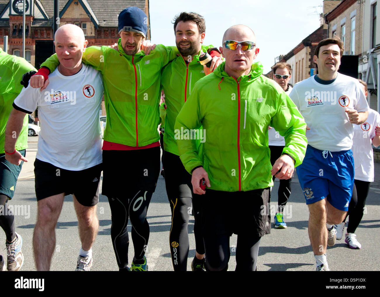 Liverpool, Regno Unito. Il 6 aprile 2013. Steve Kelly dall'Hillsborough giustizia Camapign (L) e Scott Cunliffe (3 L) tenere runner Dominic Williams fino durante l ultima tappa di una 96 miglio carità corrono tra Hillsborough e Anfield Credito: Andy Thornley / Alamy Live News Foto Stock