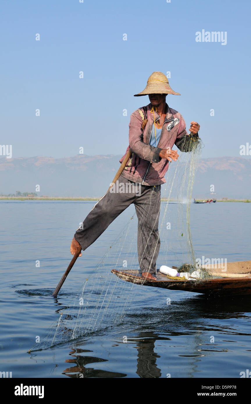 Fisherman con net il canottaggio la sua barca con una gamba, Lago Inle, Stato Shan, Myanmar, sud-est asiatico Foto Stock