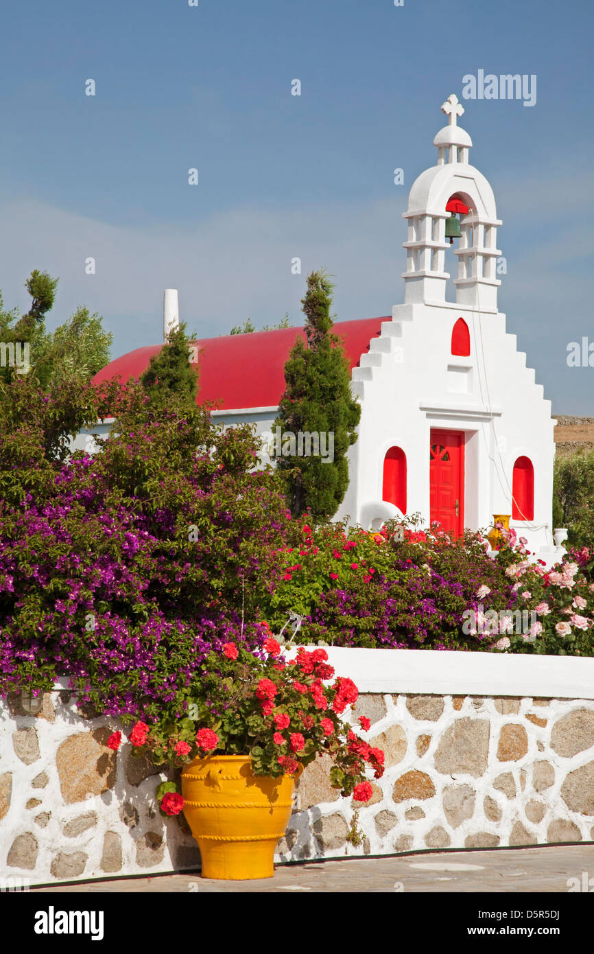 Piccola cappella greca, campanile e giardino con bougainvillea e gerani nella campagna dell'isola di Mykonos, Grecia Foto Stock