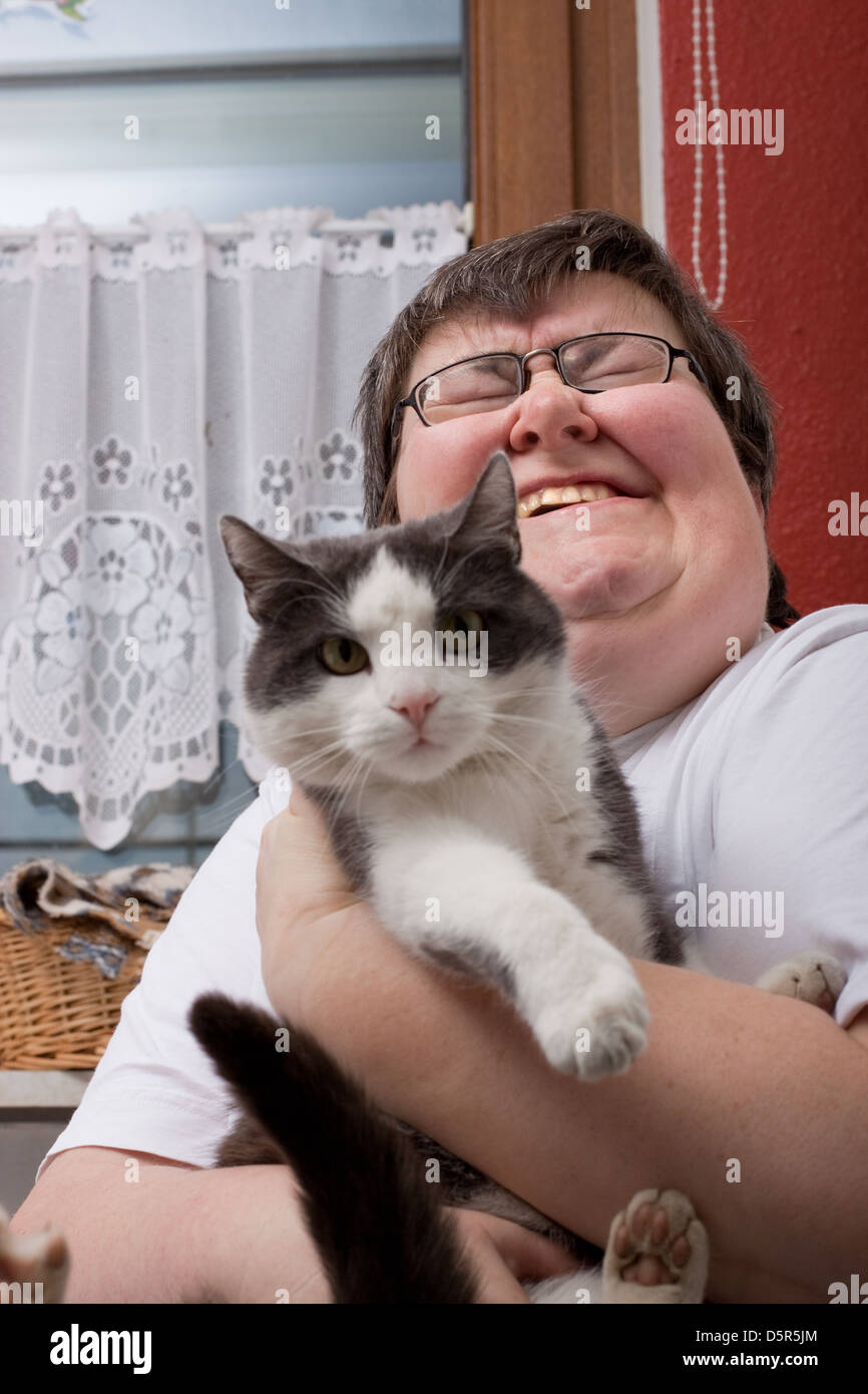 Una seduta disabili mentali della donna è in possesso di un gatto Foto Stock