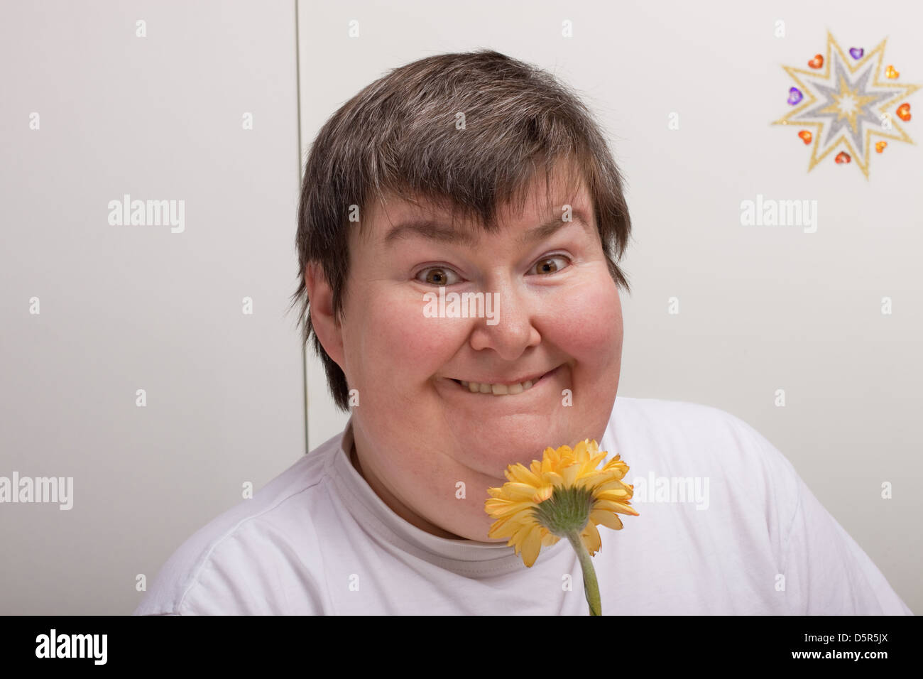 Una seduta disabili mentali donna è odore di un fiore Foto Stock