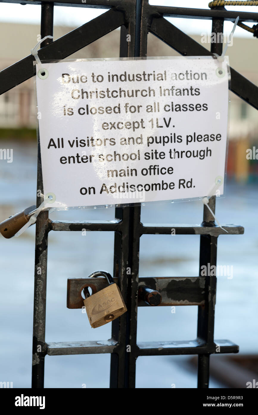 Scuola chiusa a causa della azione industriale segno su cancelli chiuso con lucchetto Foto Stock