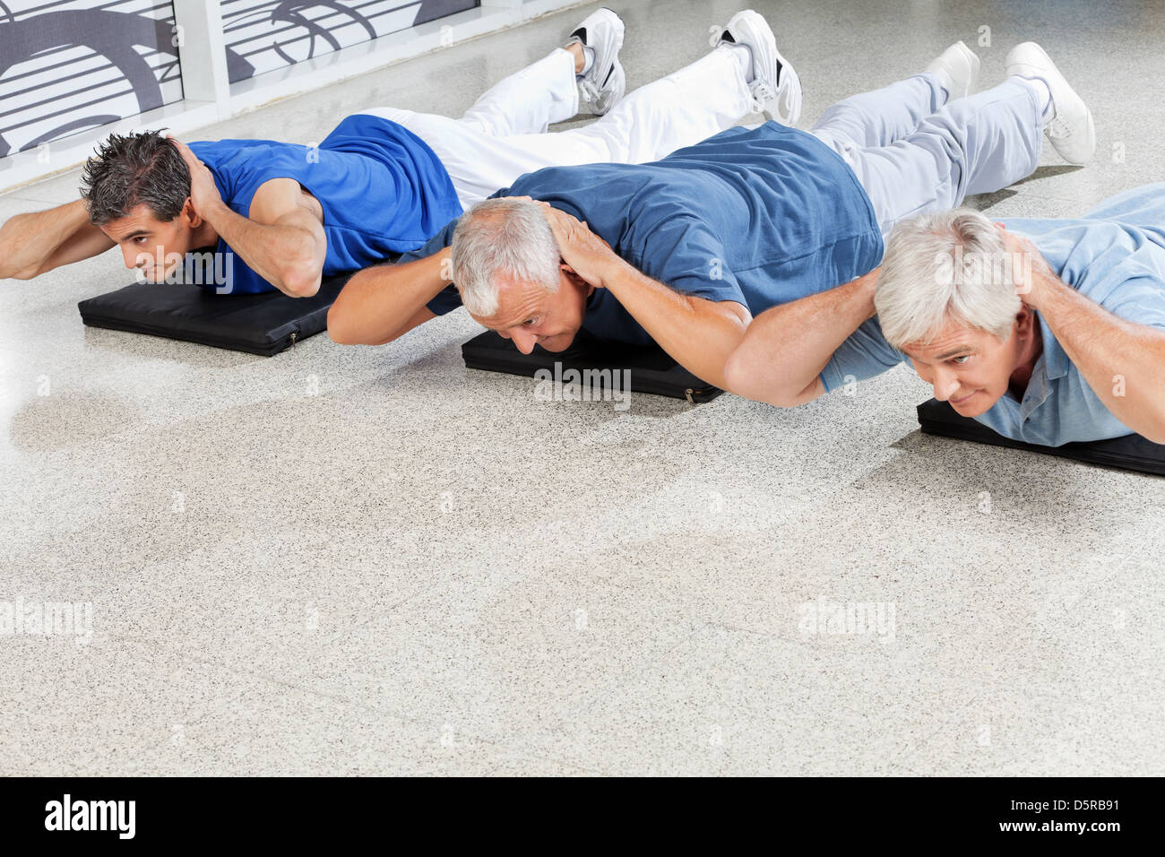 Uomini anziani facendo esercizi per la schiena in un centro fitness Foto Stock
