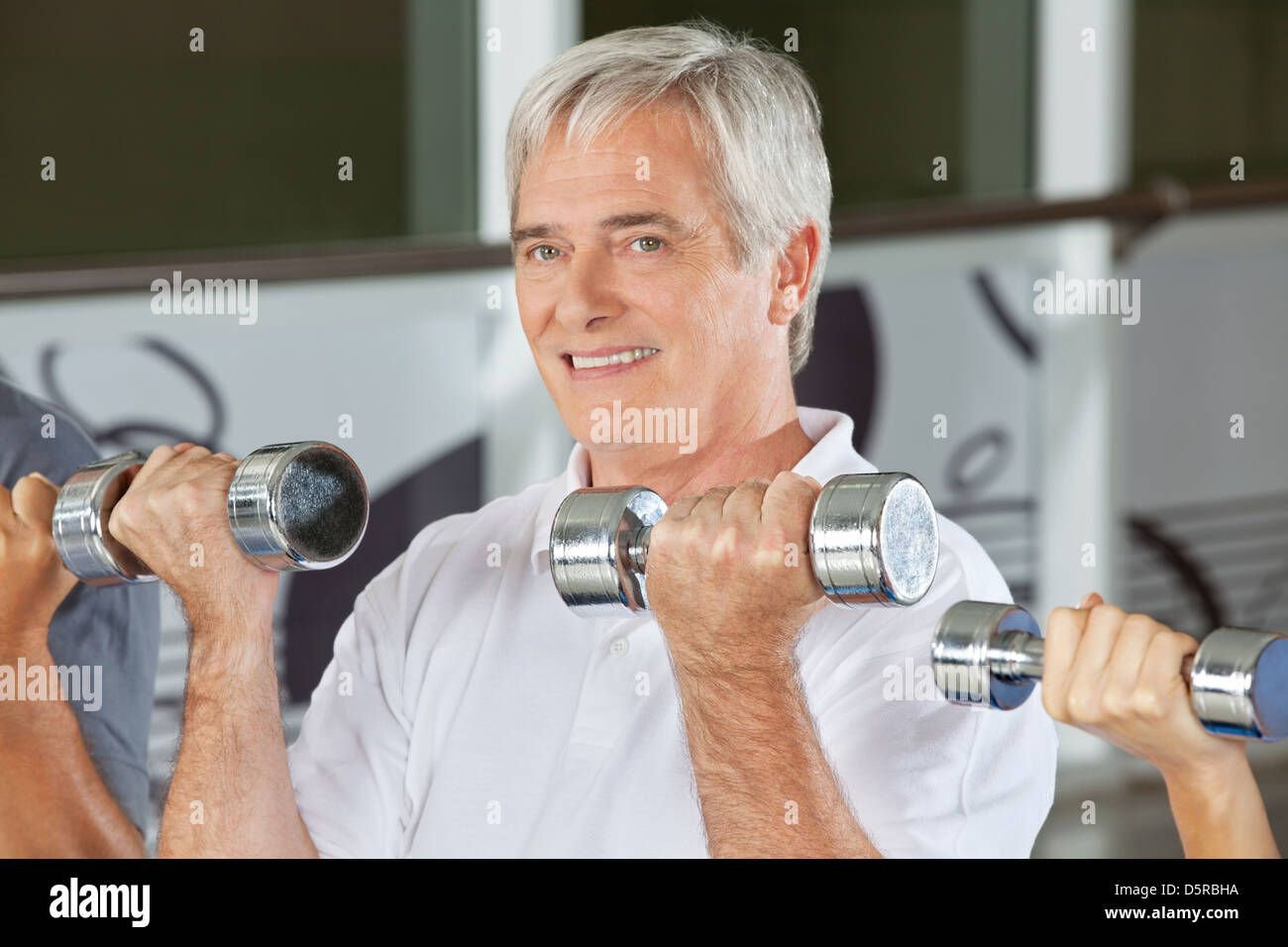 Senior uomo facendo dumbbell formazione nel centro fitness Foto Stock