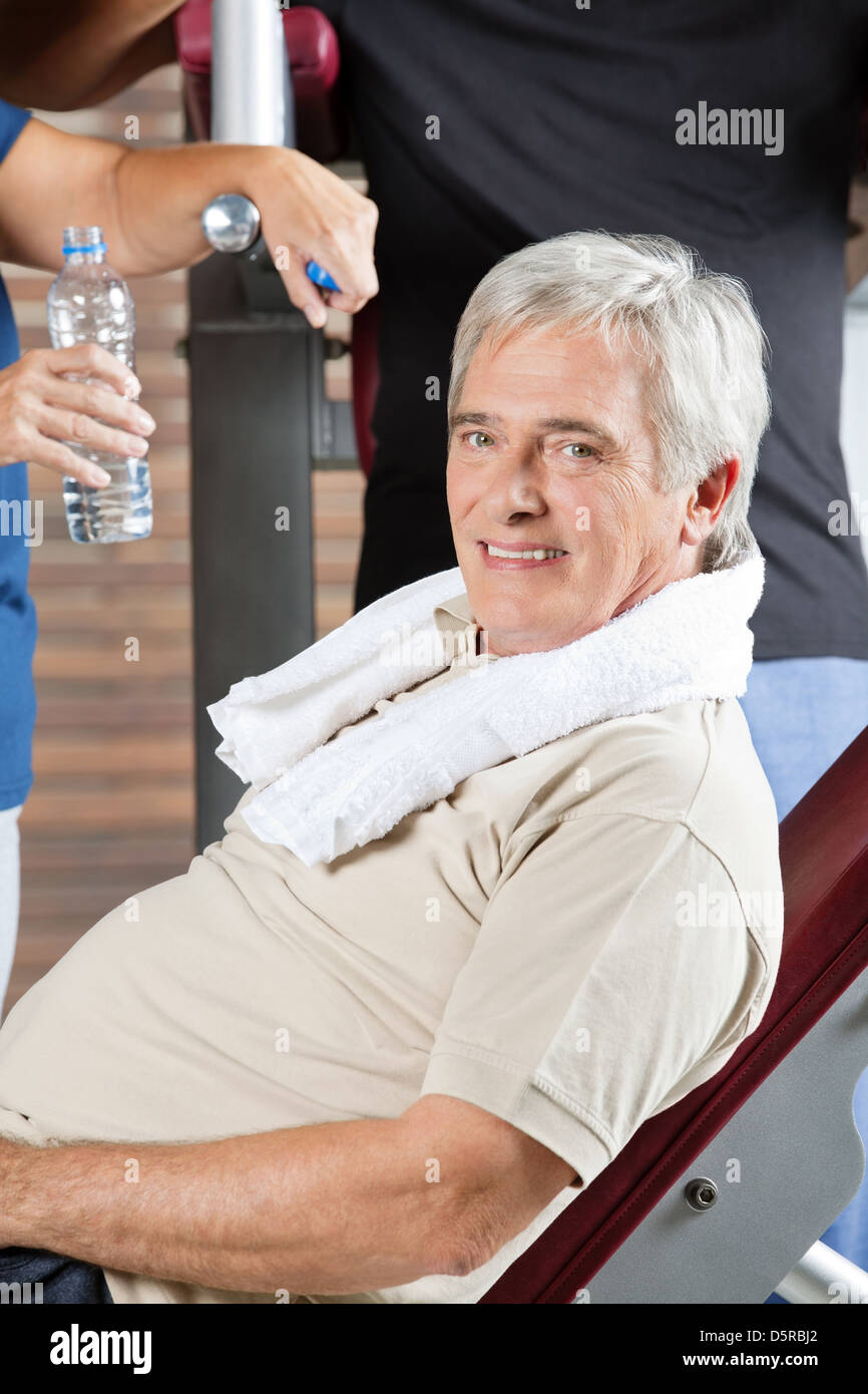Uomo anziano con asciugamano rilassante sulla panchina nel centro fitness Foto Stock