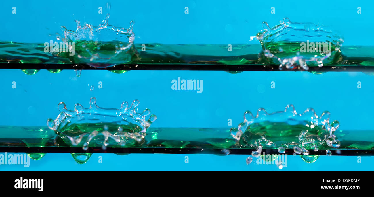 Gli spruzzi di acqua scende su sfondo blu Foto Stock