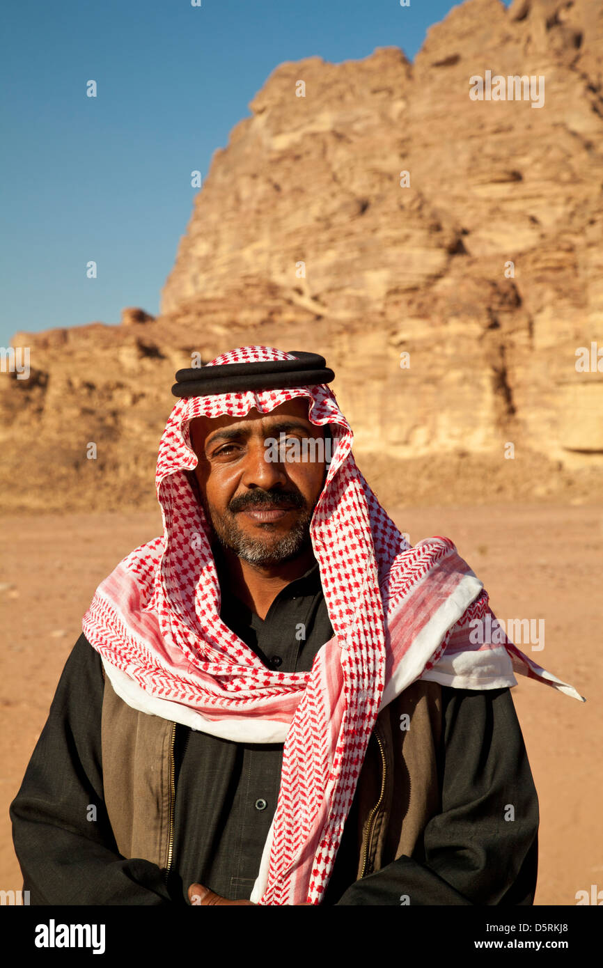 Un beduino uomo che indossa il rosso-e-bianco keffiyeh a scacchi sciarpa a Wadi Rum, Giordania Foto Stock