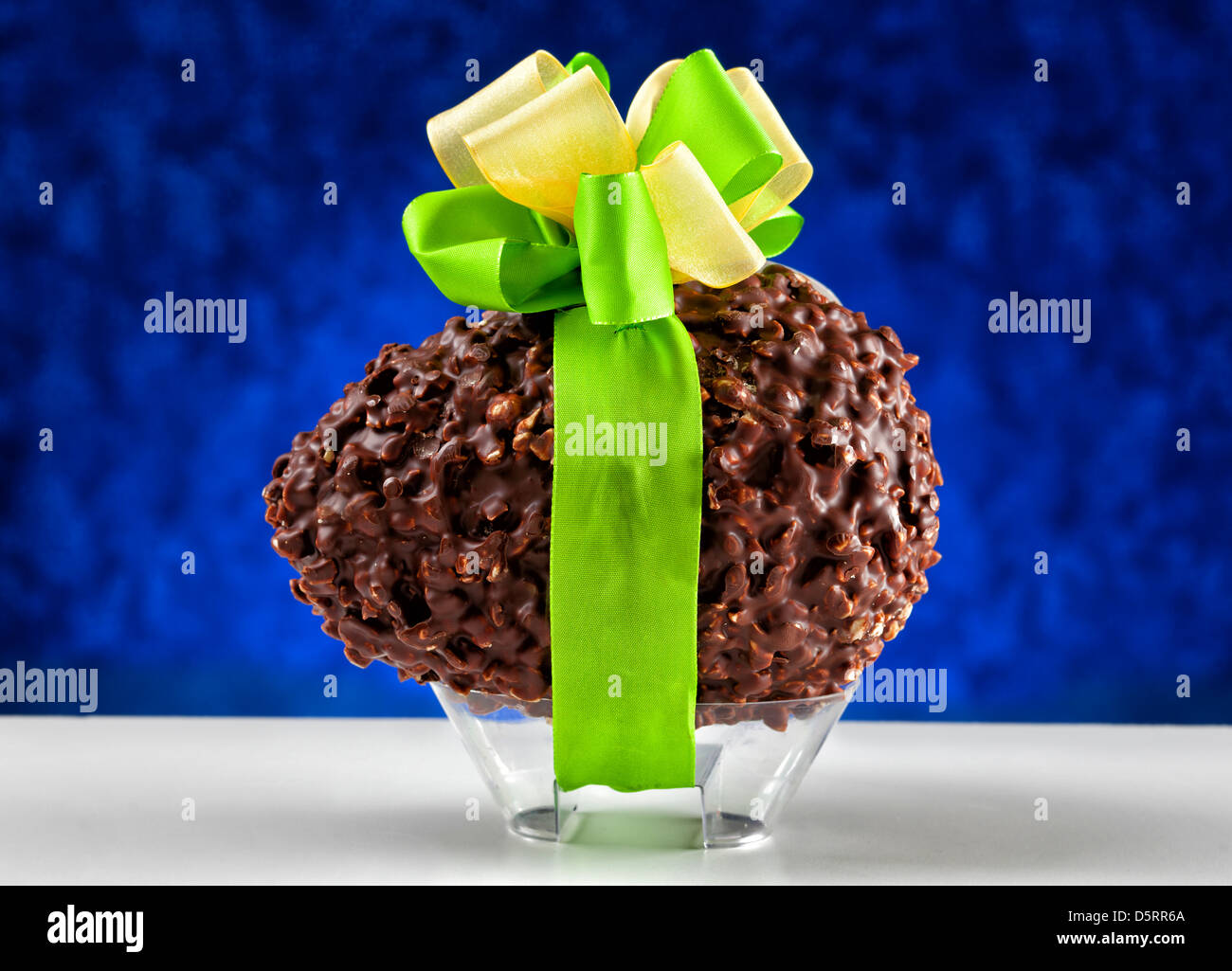 Uovo di cioccolato con dadi su sfondo blu Foto Stock