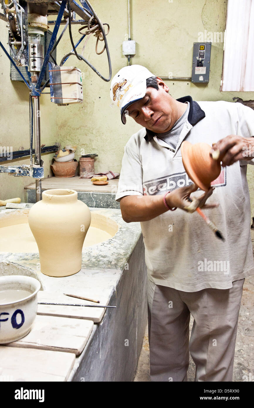 Lavoratore esperto prepara il coperchio della pentola che ha ricevuto per primo smalto Uriarte Talavera factory Pueblo Messico Foto Stock