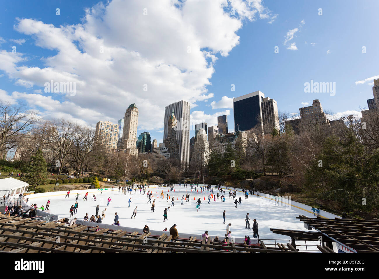 Persone il pattinaggio su un anello di ghiaccio a Central Park di New York City con edifici in background Foto Stock