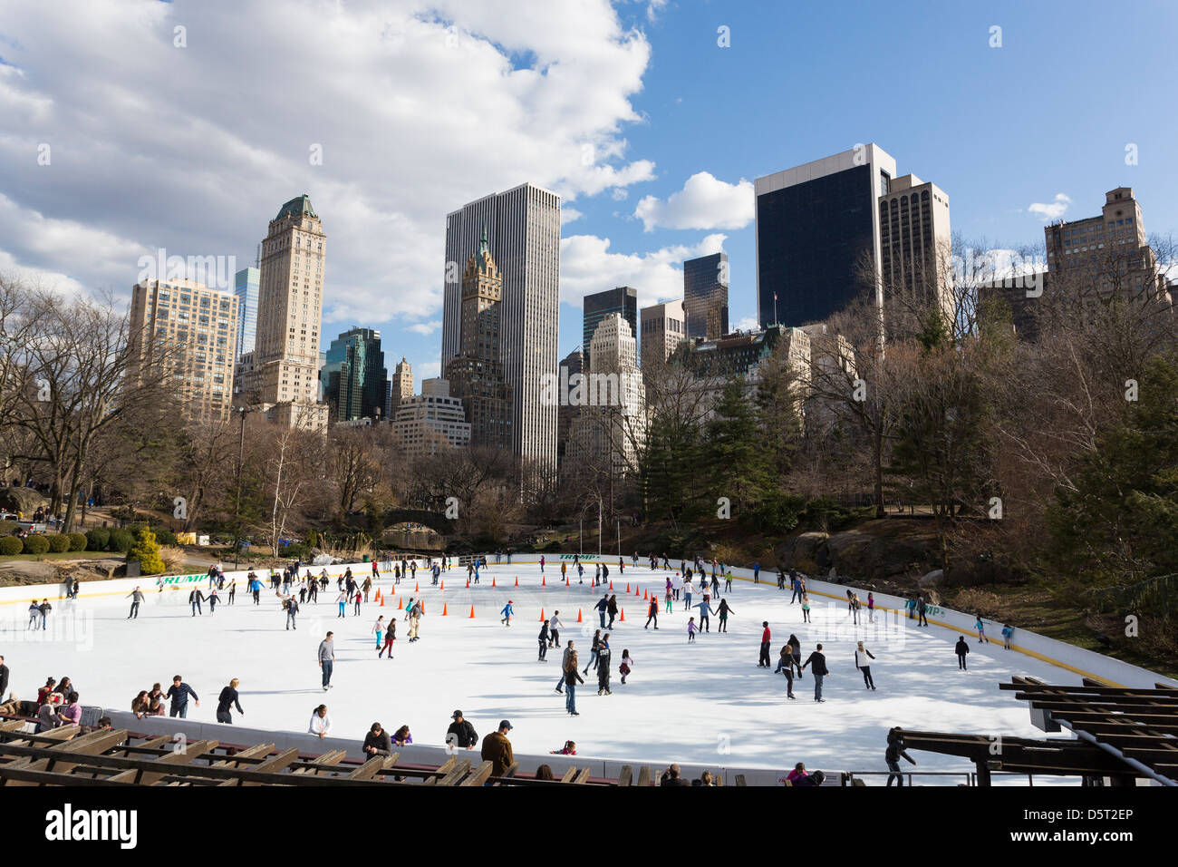 Persone il pattinaggio su un anello di ghiaccio a Central Park di New York City con edifici in background Foto Stock