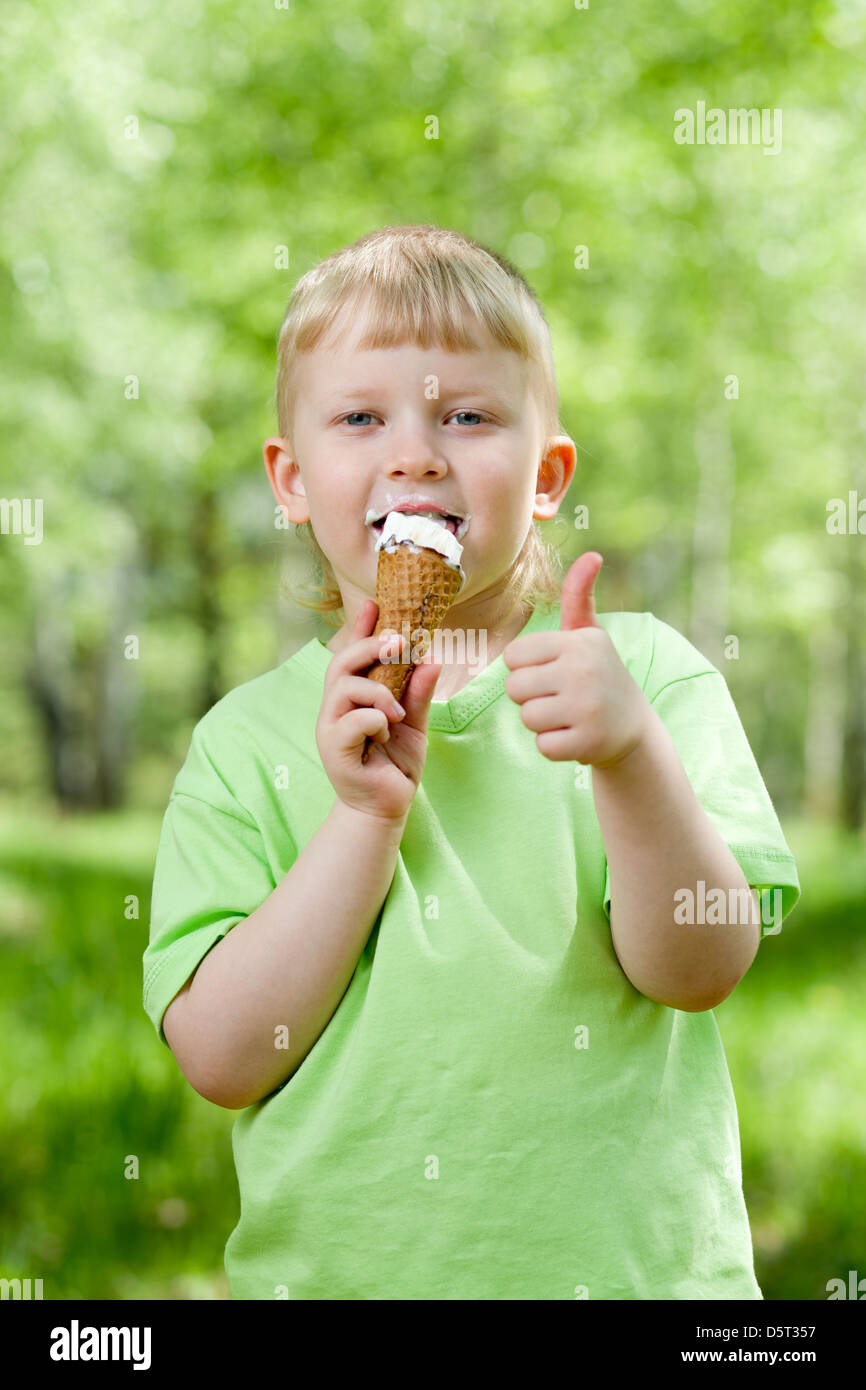 Kid mangiare un gustoso gelato outdoor e mostrando il pollice in alto Foto Stock