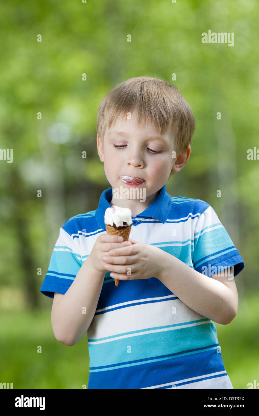 Bambino felice di mangiare un gustoso gelato all'aperto Foto Stock