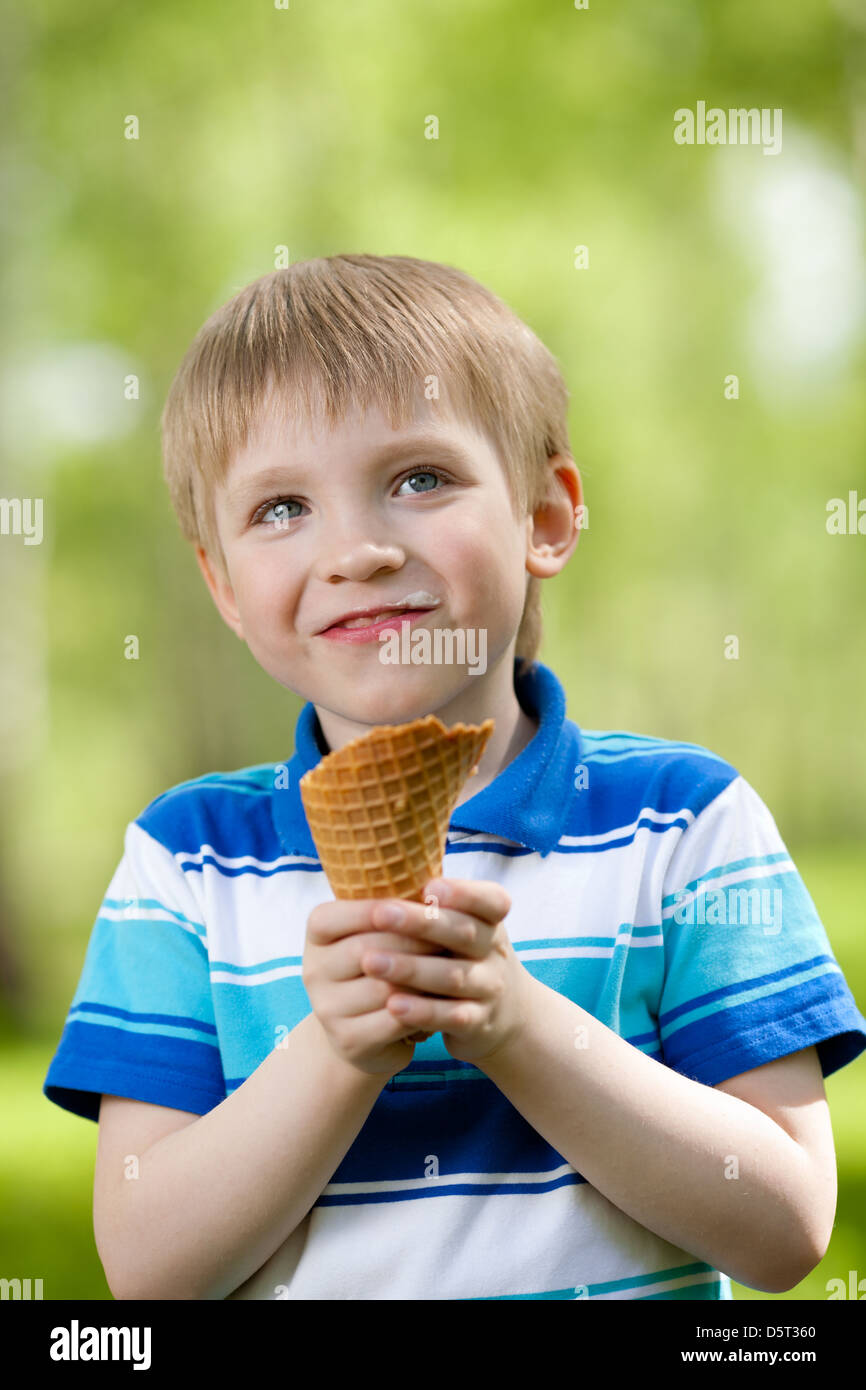 Ritratto di giovane ragazzo di mangiare un gustoso gelato all'aperto Foto Stock