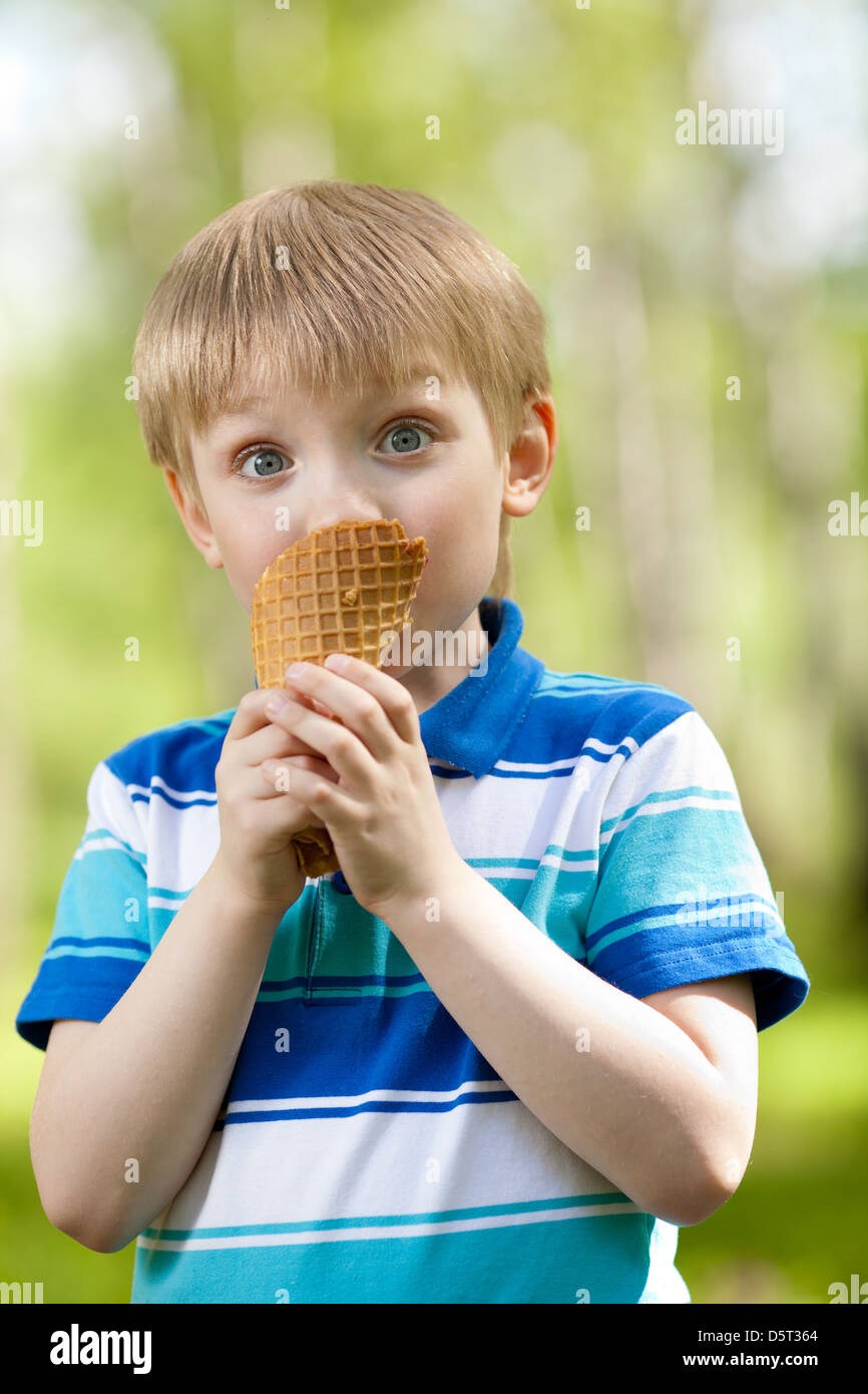 Divertenti ragazzo bambino mangiare un gustoso gelato all'aperto Foto Stock