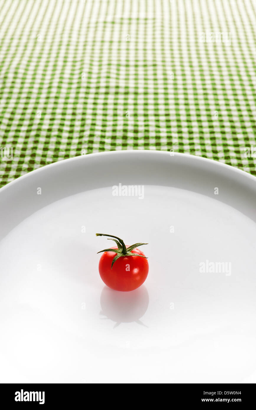 Red Cherry Pomodoro su una piastra bianca sul tavolo da cucina. Cibo organico e concetto di dieta. Foto Stock
