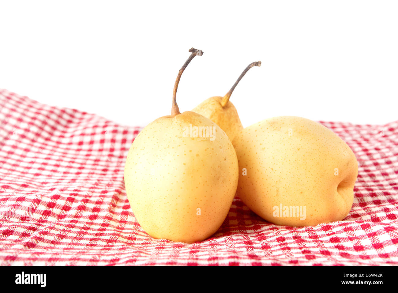 Giallo gustoso frutto di pera su un tavolo da cucina con il rosso e bianco tovaglia a scacchi. Foto Stock