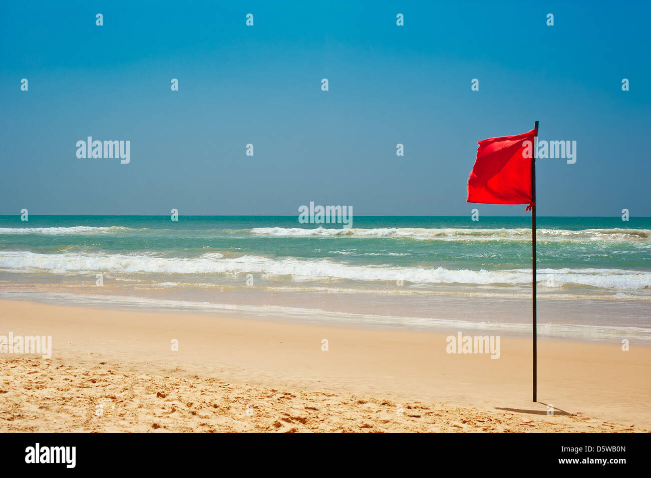 Il nuoto è pericoloso in onde dell'oceano. Red Flag di avviso sbattimenti nel vento sulla spiaggia di maltempo Foto Stock