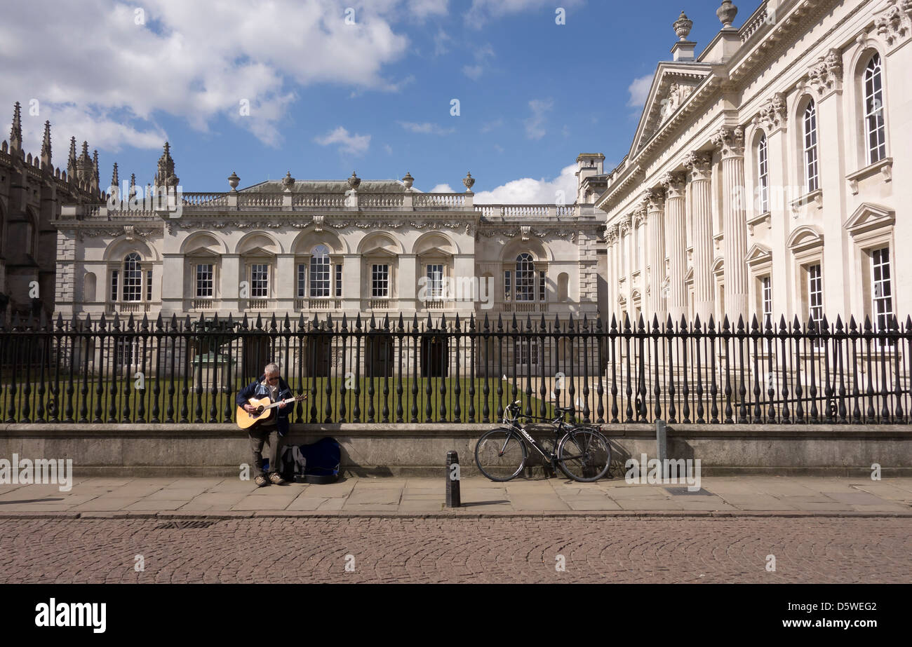 Animatore di strada suonando la chitarra nella parte anteriore della vecchia legge le scuole della città di Cambridge Inghilterra Foto Stock
