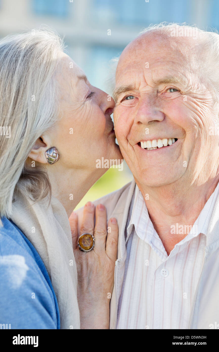 Sorridente coppia di anziani kissing all'aperto Foto Stock