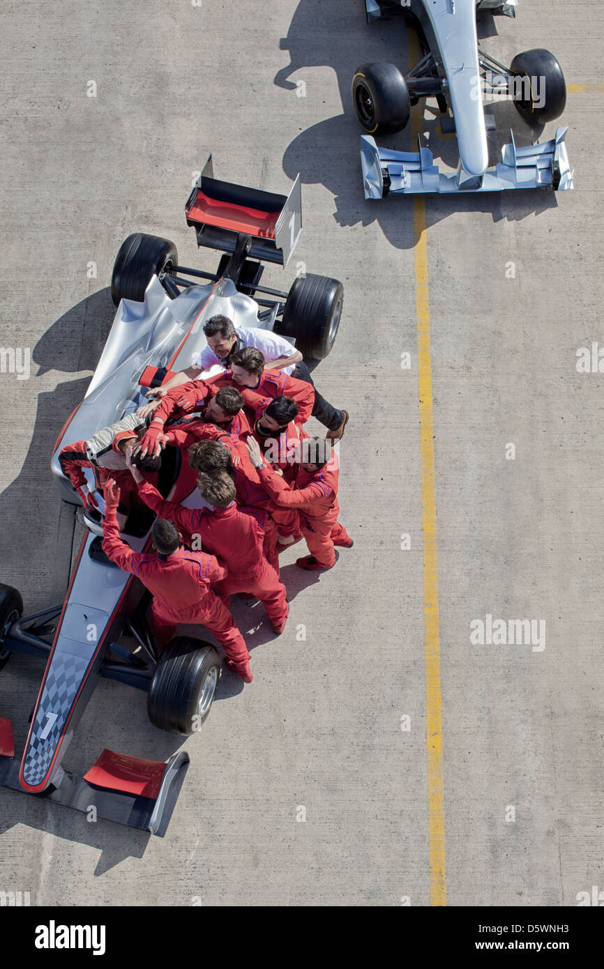 Team di gara che circonda racer su via Foto Stock