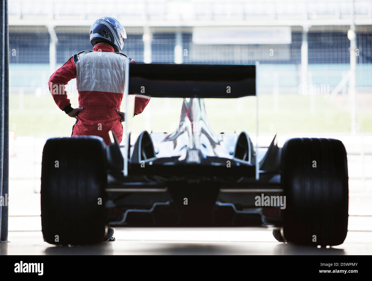 Racer in piedi con le auto in garage Foto Stock