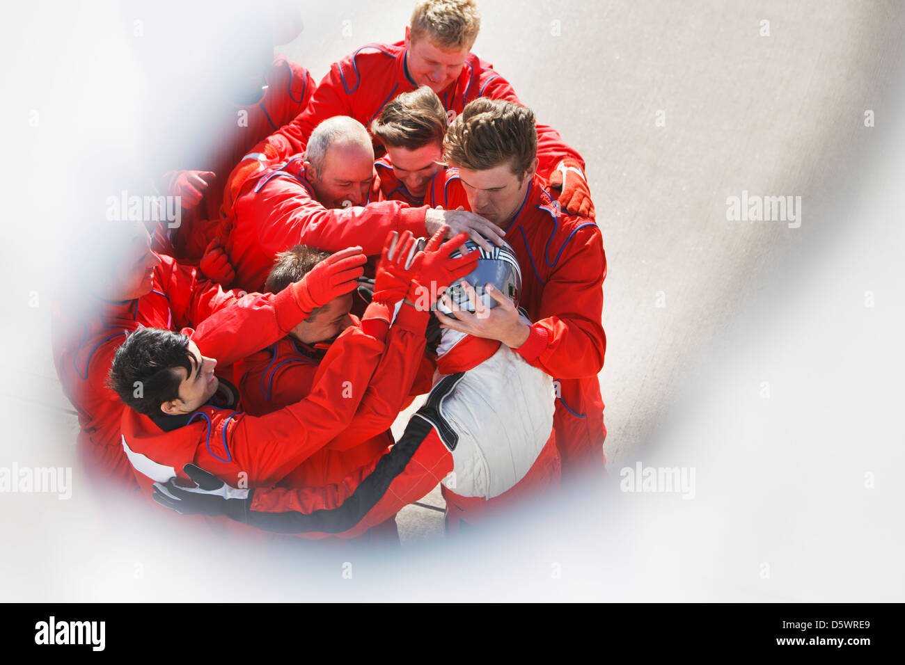 Racing team abbracciando racer al pit stop Foto Stock