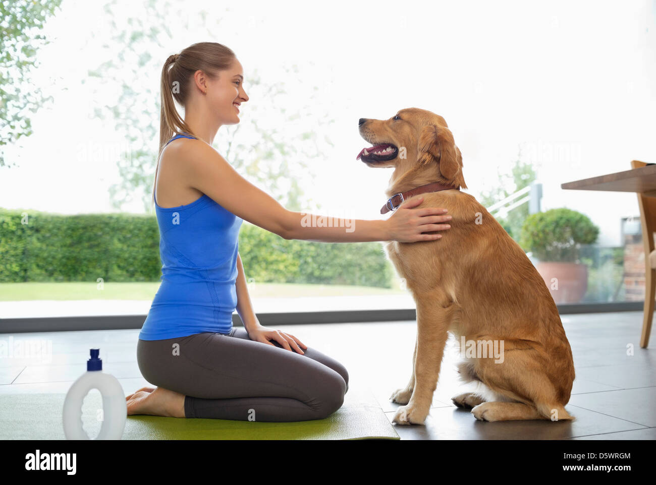 Donna pratica lo yoga con il cane in salotto Foto Stock