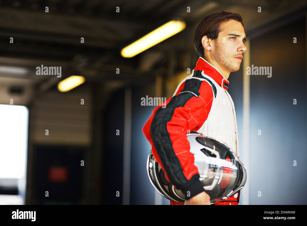 Racer holding casco in garage Foto Stock