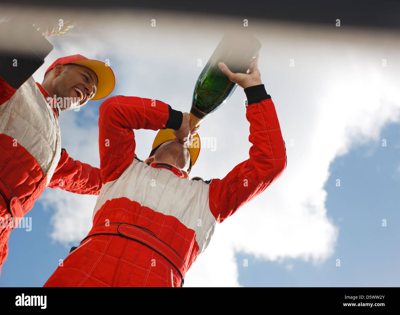 Racer bevendo champagne sulla via Foto Stock