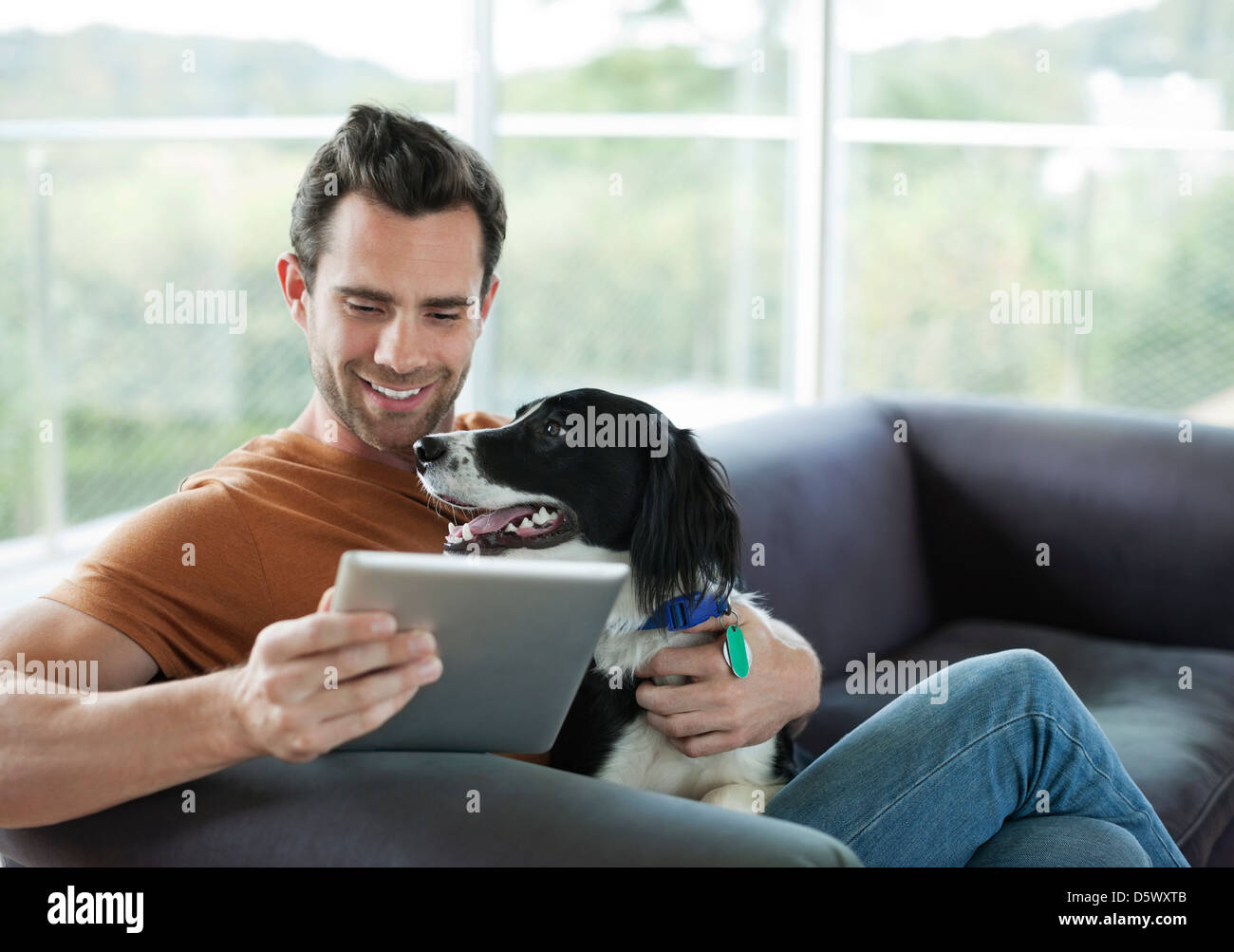 L'uomo petting cane e utilizzando computer tablet Foto Stock