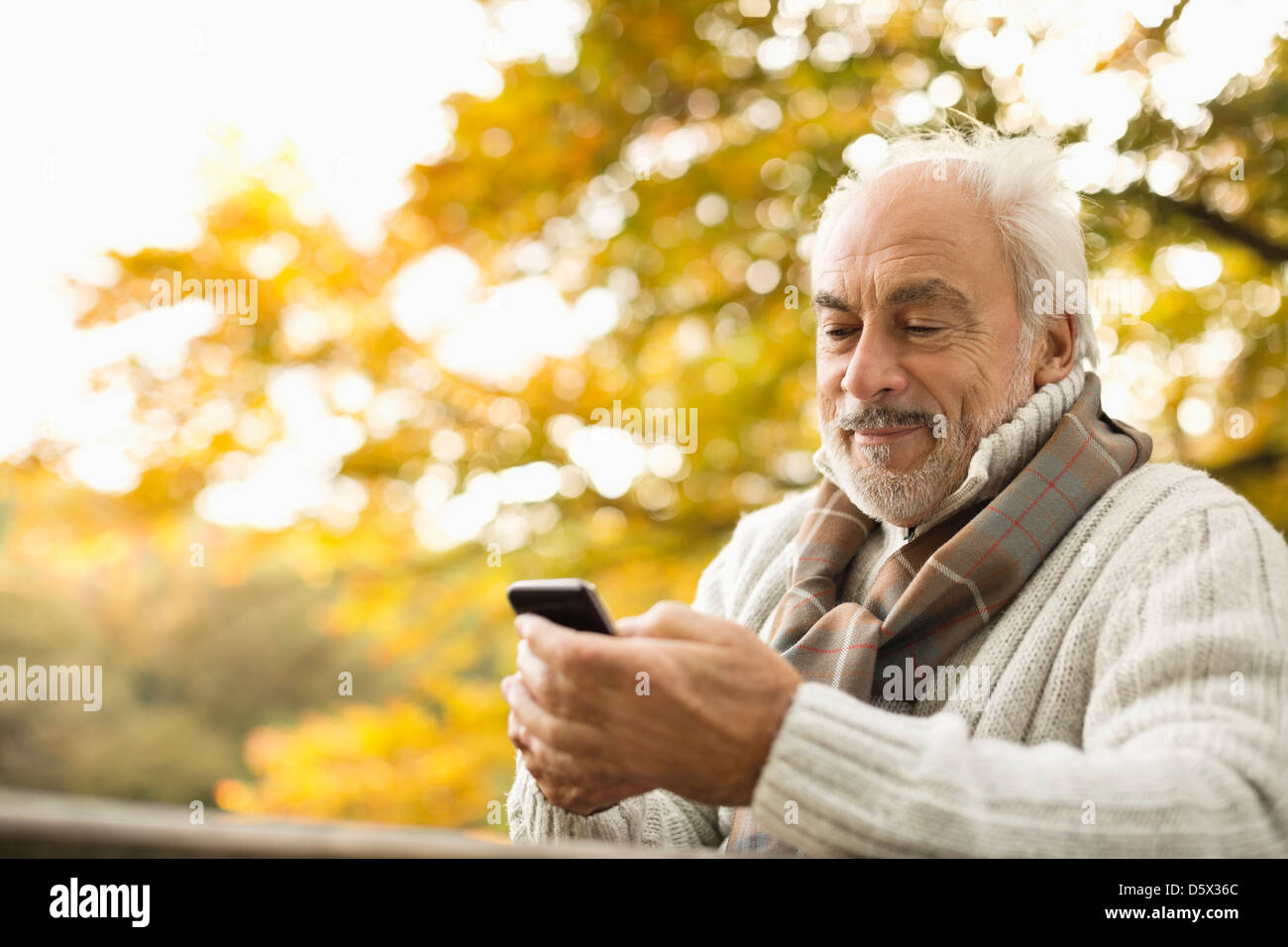 Uomo anziano tramite telefono cellulare all'aperto Foto Stock