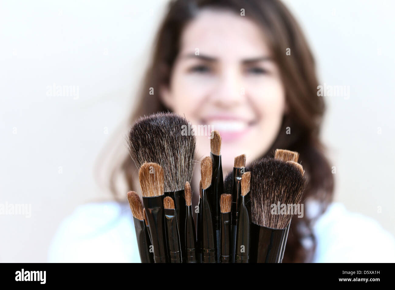 Felice giovane donna che mostra una varietà di pennelli per il trucco Foto Stock