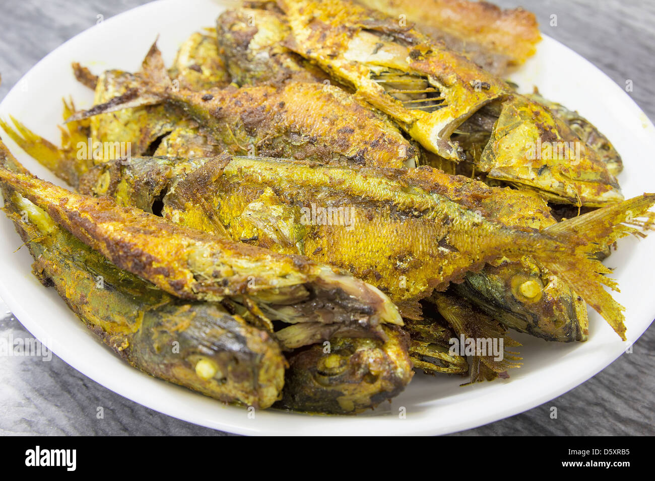 Profondo fritto intero Selar Kuning pesce con curry in polvere Closeup Foto Stock