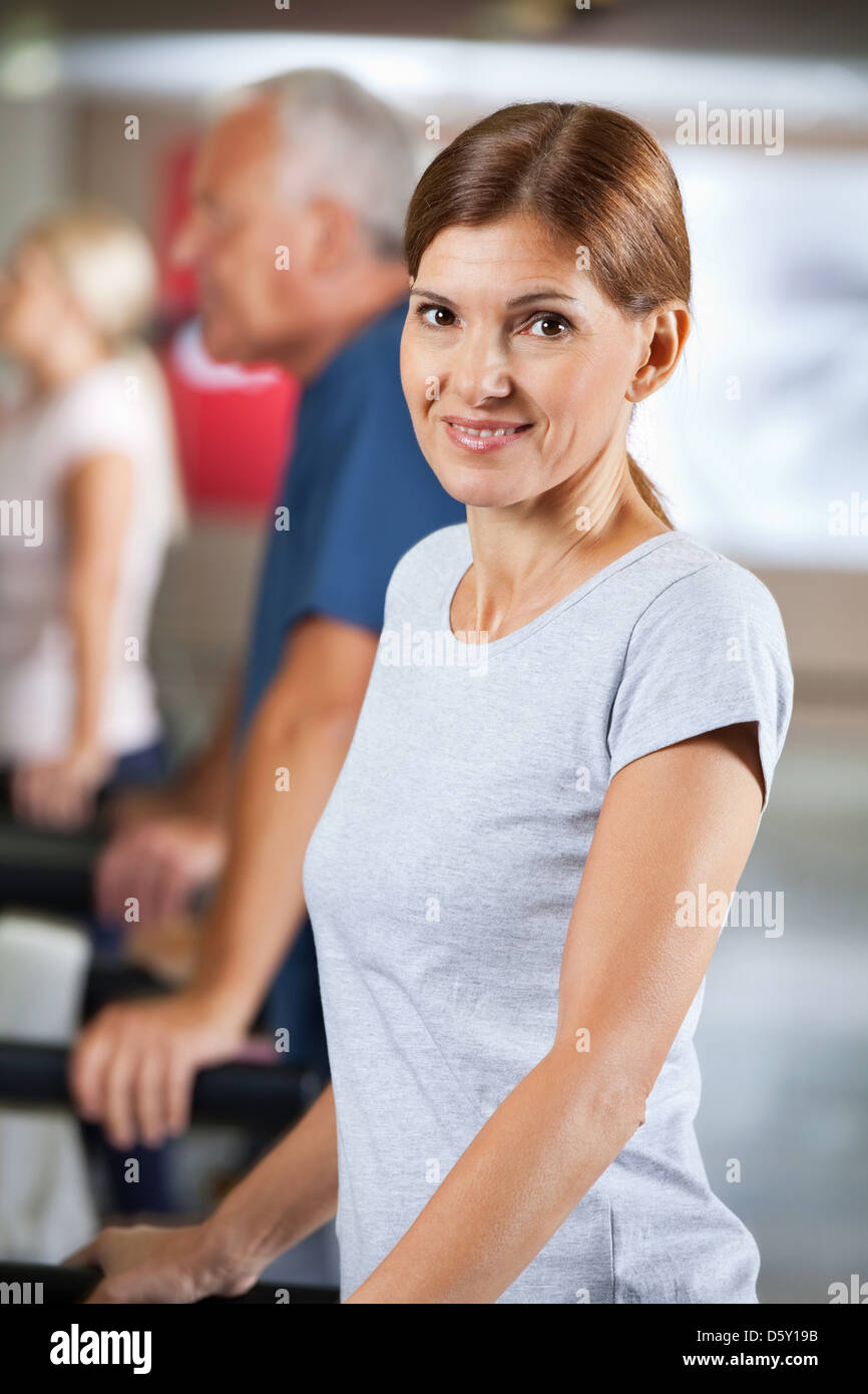 Felice donna anziana in esecuzione sul tapis roulant nel centro fitness Foto Stock