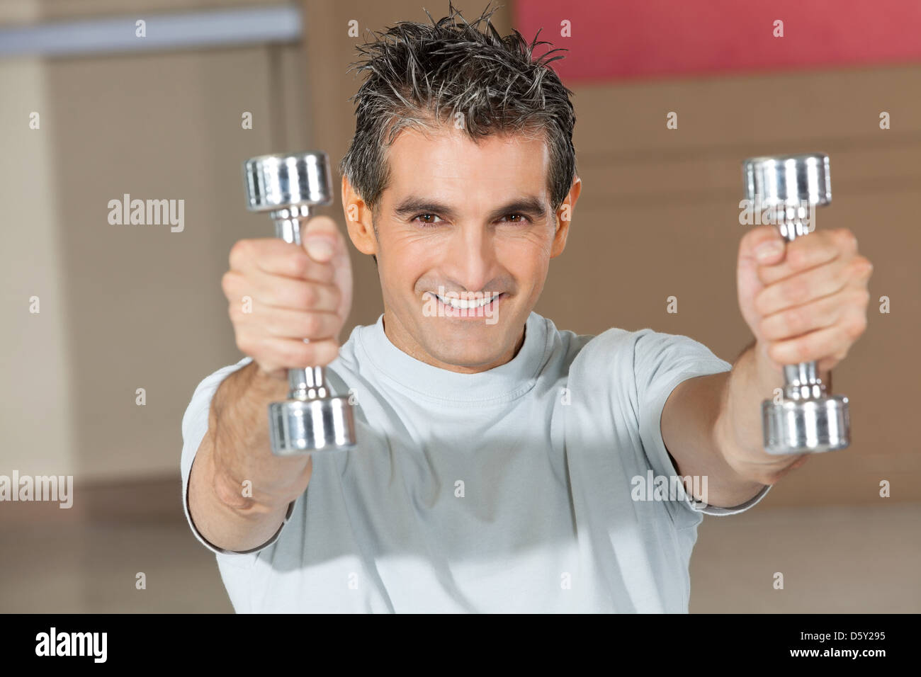Felice l'uomo utilizzando pesi nel centro fitness per gli esercizi Foto Stock