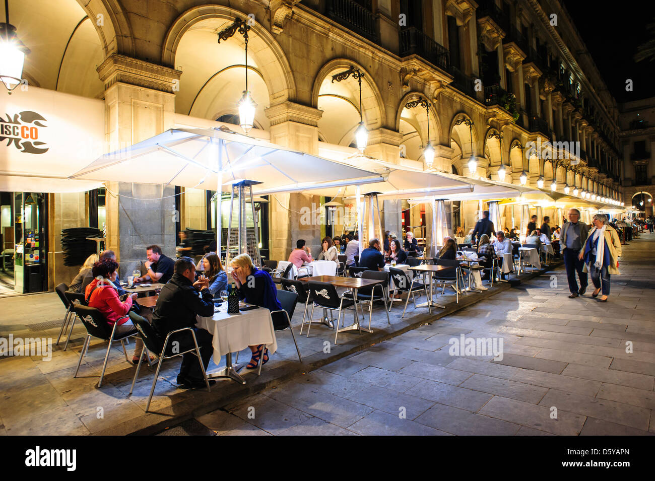 Persone di sedersi nella terrazza di un ristorante a 'Plaza Real' di Brcelona, Spagna. Foto Stock