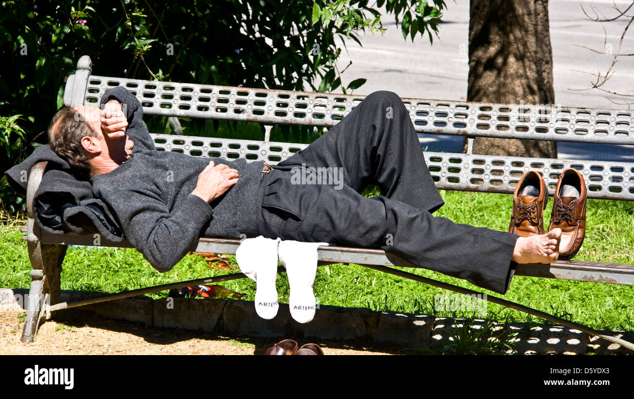 Persone di mezza età imprenditore avente una siesta dormire riposo nap snooze sul parco banco sedile Siviglia Andalusia Andalusia Spagna Europa Foto Stock
