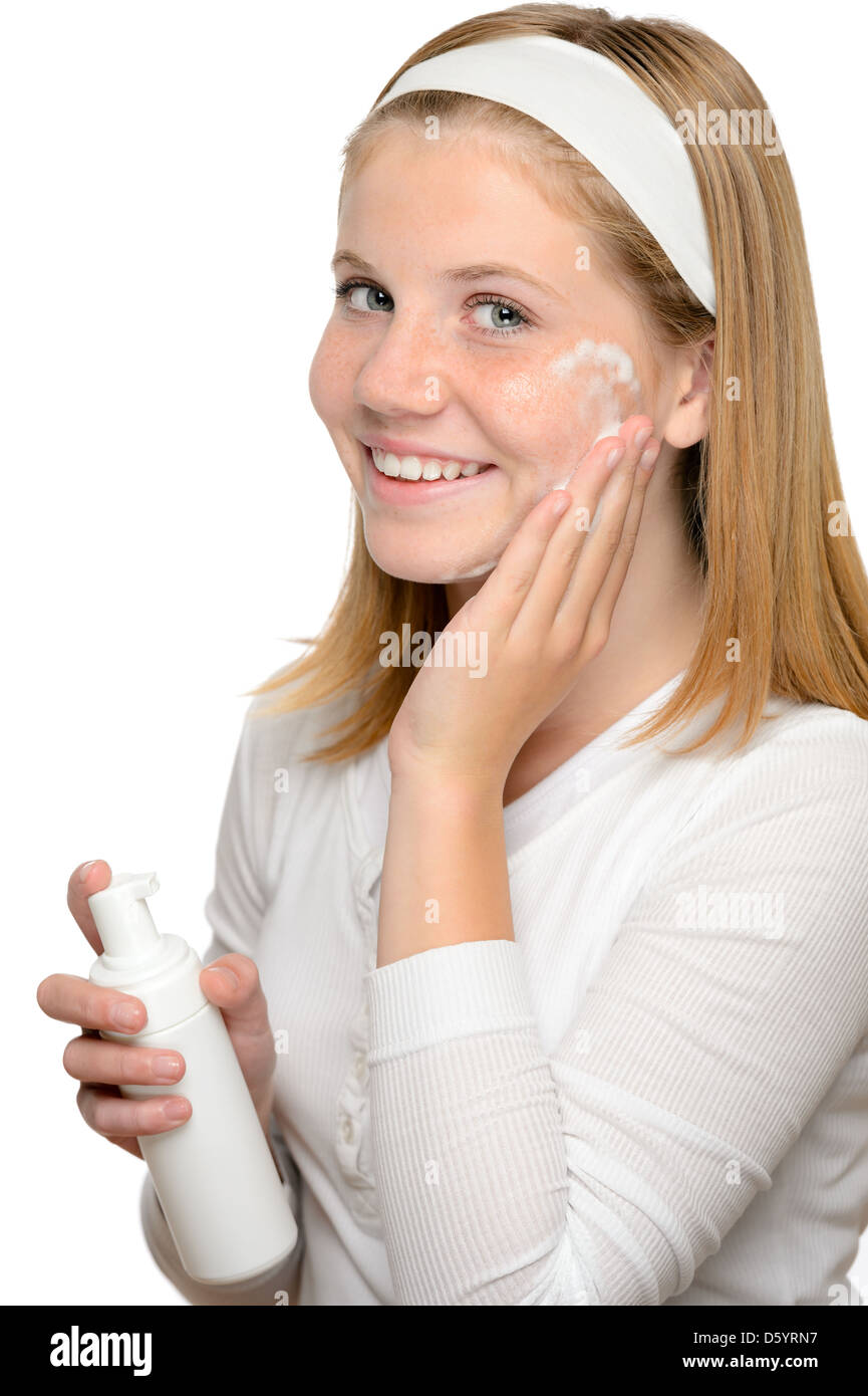 Adolescente ragazza sorridente di applicare una crema idratante viso lozione per il trattamento della pelle Foto Stock