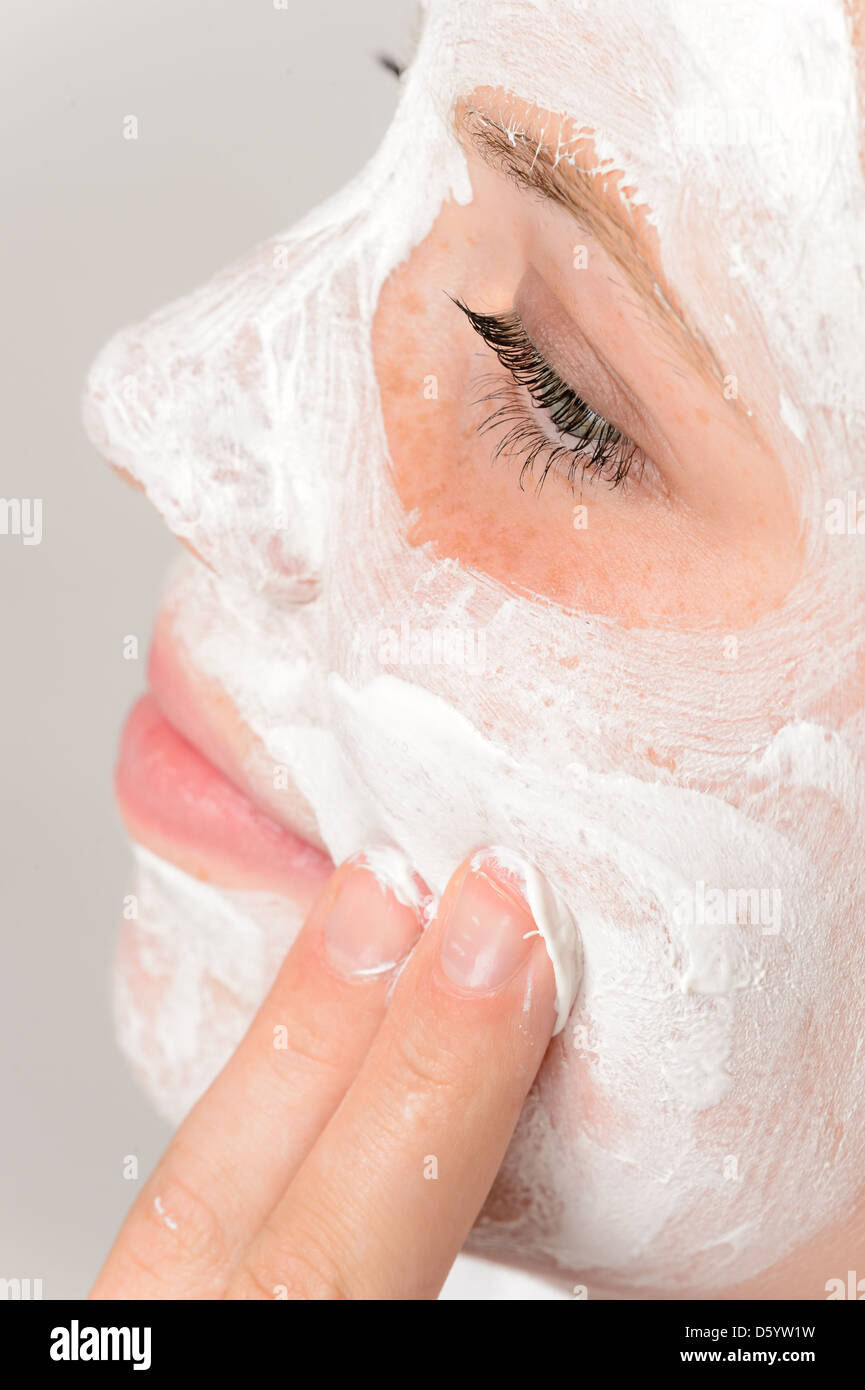 Dita di applicare la maschera per il viso idratante crema ragazza giovane trattamento di bellezza Foto Stock