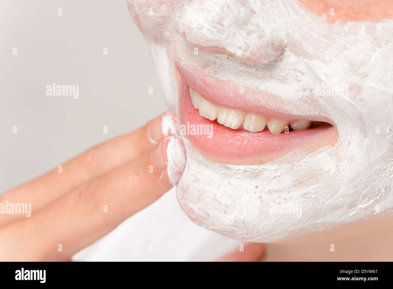 Ragazza sorridente mettendo la maschera facciale dita di trattamento di pulizia bellezza Foto Stock