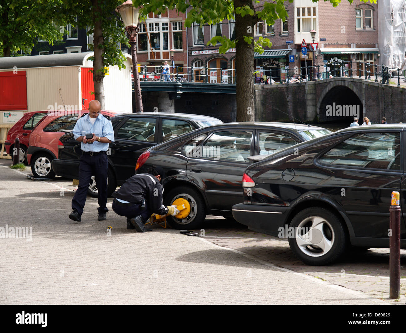 Due assistenti di parcheggio occupato di attaccare un wheelclamp sul canale Prinsengracht Amsterdam Paesi Bassi Foto Stock