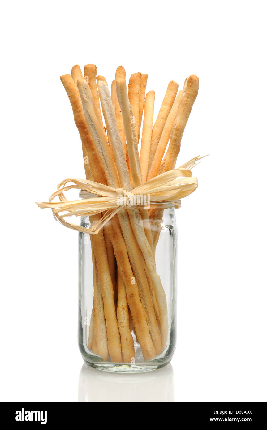 Vista dettagliata del pane italiano bastoni in un vasetto di vetro su uno sfondo bianco con la riflessione, il collo del vaso è legato con rafia. Foto Stock