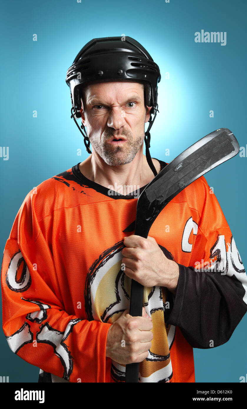 Divertente colpo di un giocatore di hockey appoggiata sulla sua mazza da hockey rendendo un arrabbiato espressione. Foto Stock