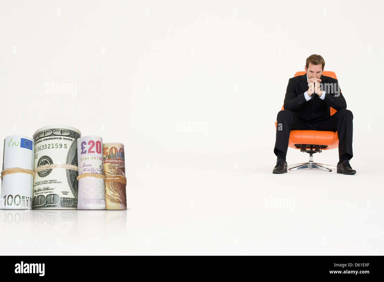Rotoli di denaro con pensieroso imprenditore sedia che rappresentano problemi finanziari Foto Stock