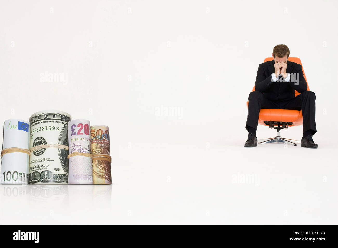 Rotoli di denaro con preoccupato imprenditore sedia che rappresentano problemi finanziari Foto Stock