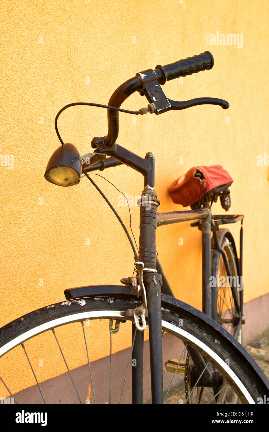 Vecchio vintage bicicletta nero appoggiato sulla parete. Foto Stock