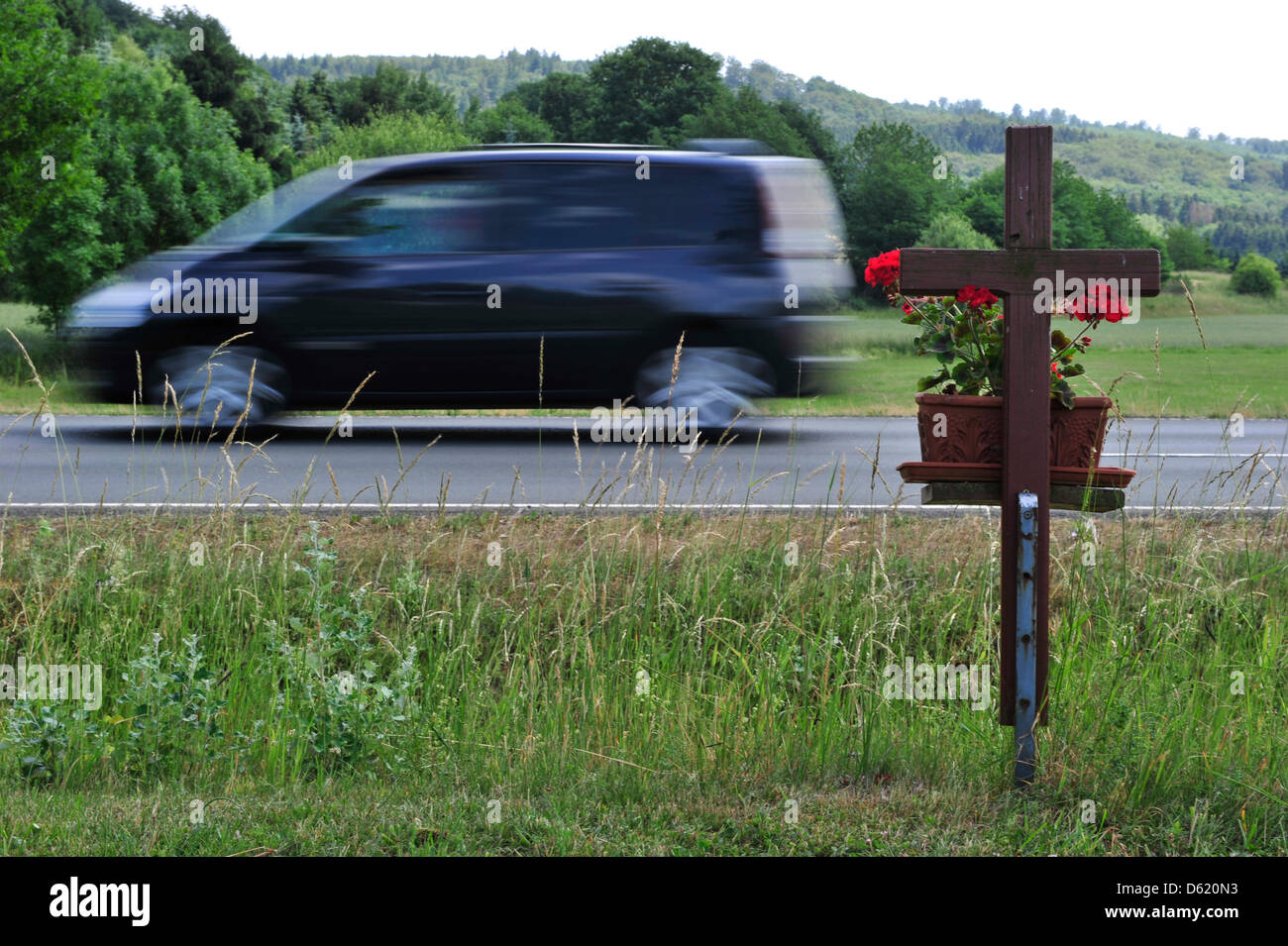 Una unità auto passato una croce in corrispondenza della strada di Marburg, Germania, il 7 giugno 2011. A partire dal 2011, la strada pedonale di tasso di morte ha salito, proprio come il numero di decessi di traffico in generale. Consulenti di protezione richiedono maggiore attenzione. Foto: Marc Tirl Foto Stock