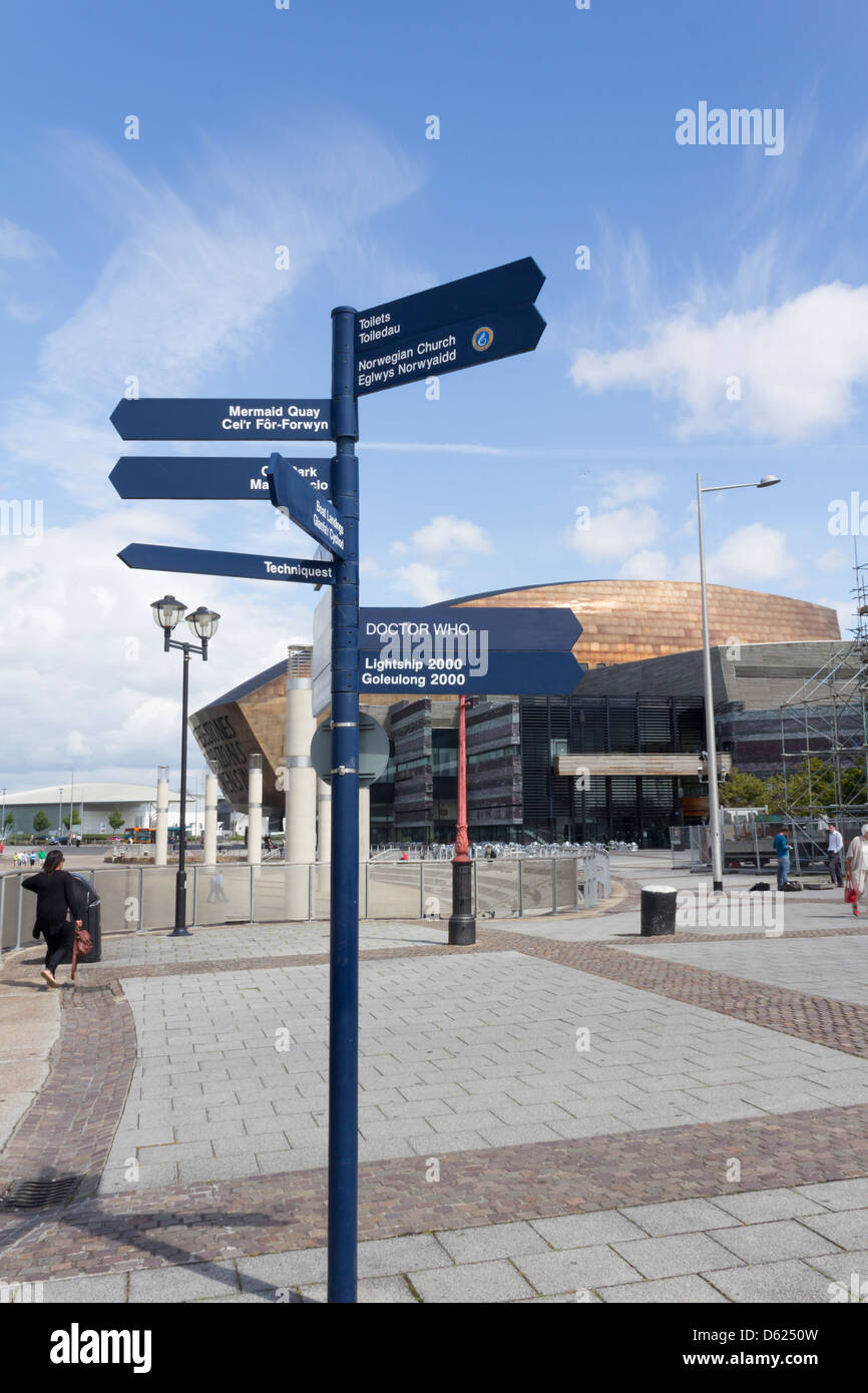 Cardiff Bay Visitor signpost su Roald Dahl Plass in doppia lingua gallese e inglese. Al di là è il Wales Millennium Centre. Foto Stock